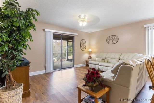 living room featuring ceiling fan, light hardwood / wood-style flooring, and a textured ceiling