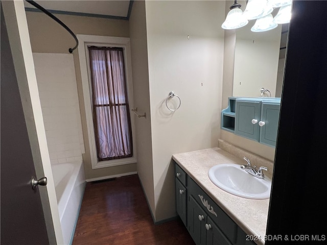 bathroom featuring hardwood / wood-style flooring, vanity, and washtub / shower combination