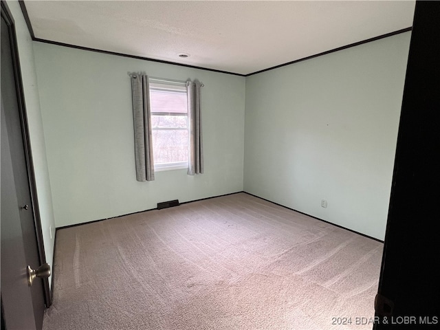 empty room with crown molding and light carpet