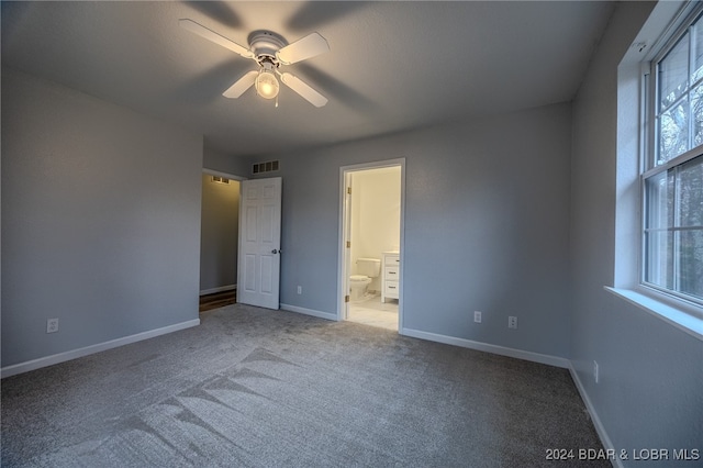 unfurnished bedroom featuring ceiling fan, ensuite bathroom, and light colored carpet