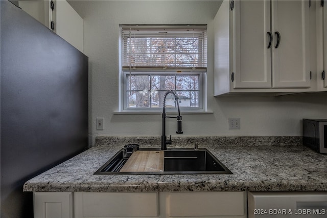 kitchen featuring white cabinetry, sink, and light stone countertops