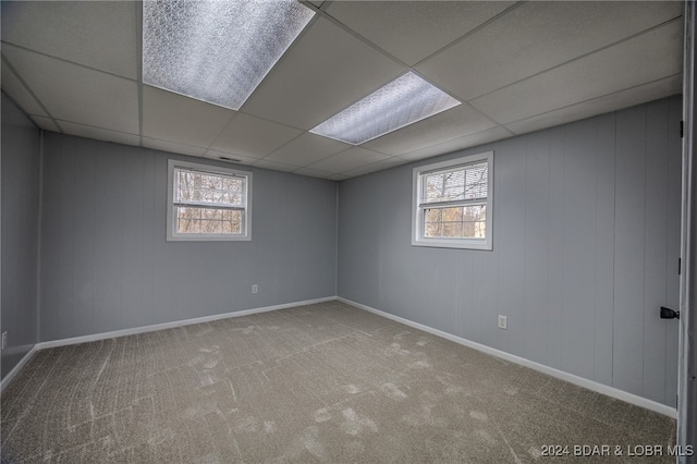 basement featuring carpet, a drop ceiling, and a healthy amount of sunlight