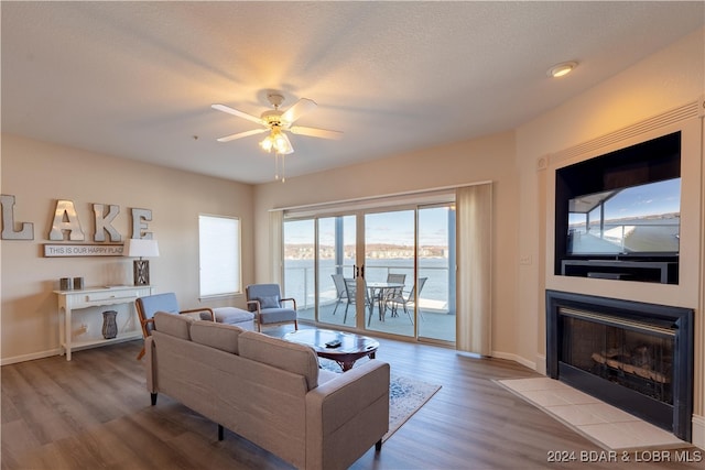 living room with ceiling fan, light hardwood / wood-style floors, and a textured ceiling