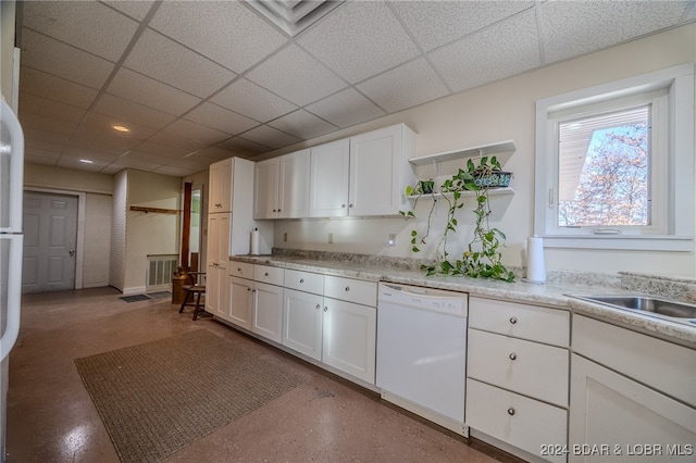 kitchen featuring white dishwasher, white cabinetry, and a drop ceiling