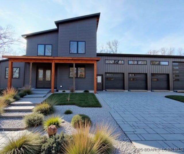 contemporary home with an attached garage, decorative driveway, and french doors