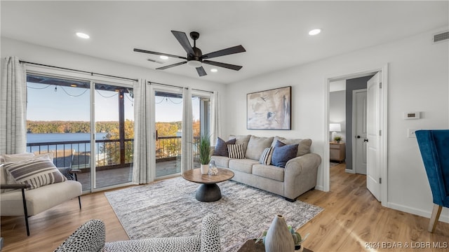 living room featuring light wood-type flooring, a water view, and ceiling fan