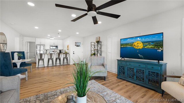 living room featuring light hardwood / wood-style flooring and ceiling fan