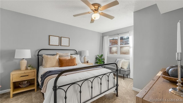 bedroom with ceiling fan, light colored carpet, and a textured ceiling