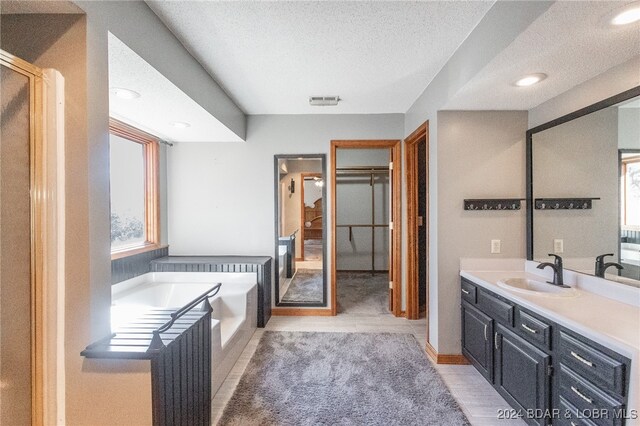 bathroom with separate shower and tub, hardwood / wood-style floors, vanity, and a textured ceiling