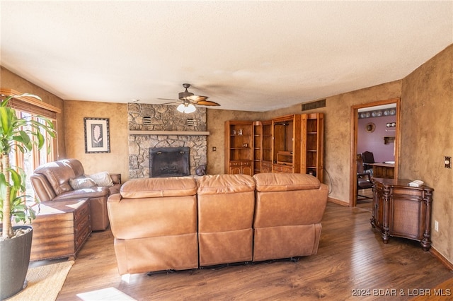 living room with a textured ceiling, ceiling fan, wood-type flooring, and a fireplace