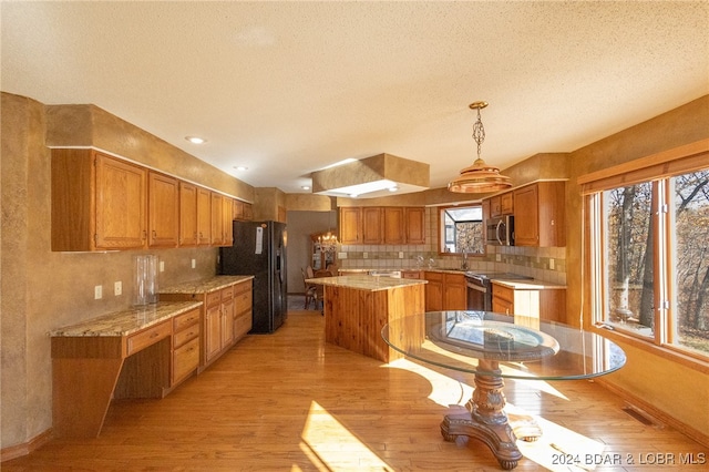 kitchen with appliances with stainless steel finishes, light wood-type flooring, sink, pendant lighting, and a kitchen island