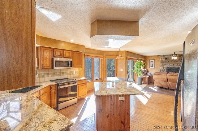 kitchen with backsplash, ceiling fan, light wood-type flooring, a textured ceiling, and appliances with stainless steel finishes