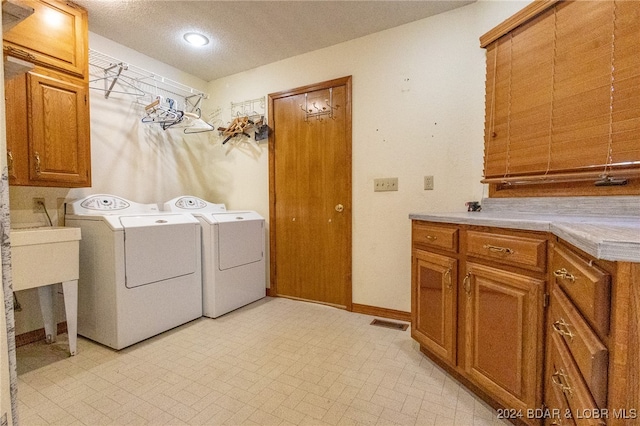 laundry room featuring cabinets, independent washer and dryer, and a textured ceiling