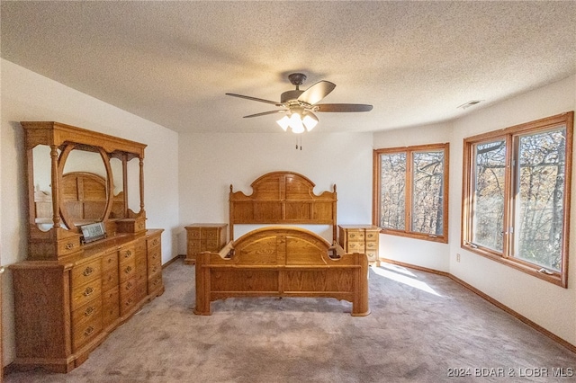 carpeted bedroom with ceiling fan and a textured ceiling