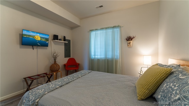 bedroom with electric panel and hardwood / wood-style flooring