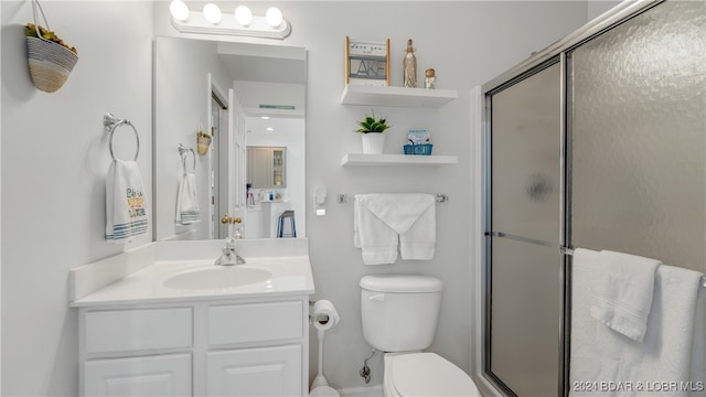 bathroom featuring vanity, toilet, and a shower with shower door