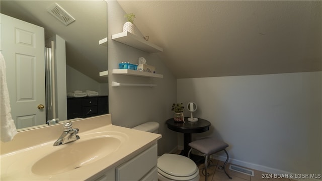 bathroom with vanity, lofted ceiling, tile patterned floors, toilet, and a textured ceiling