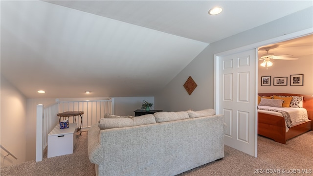 carpeted living room with ceiling fan and vaulted ceiling