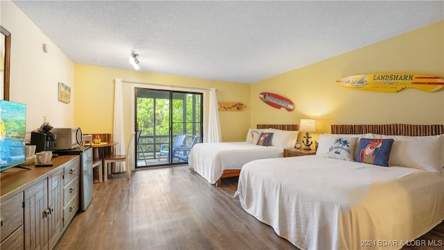 bedroom with access to outside, fridge, dark wood-type flooring, and a textured ceiling