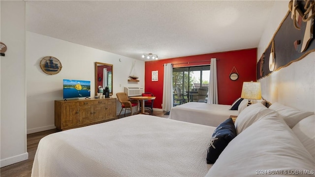 bedroom with dark hardwood / wood-style floors, access to exterior, and a textured ceiling