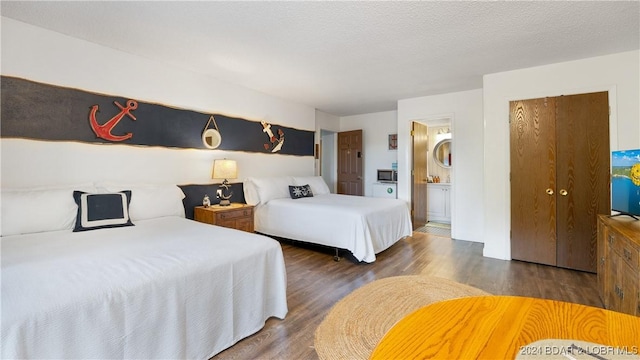 bedroom featuring a textured ceiling, dark hardwood / wood-style flooring, and ensuite bathroom