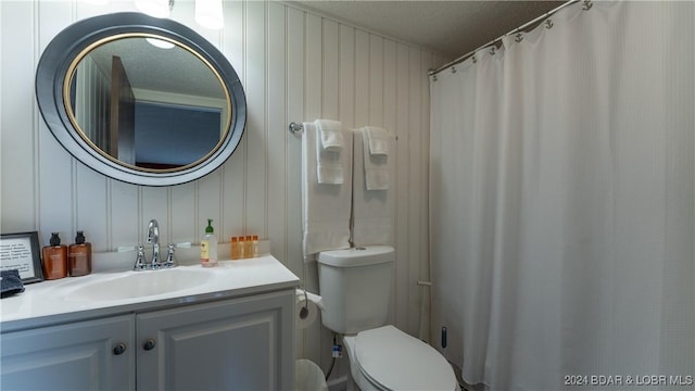 bathroom featuring a shower with shower curtain, vanity, toilet, and a textured ceiling