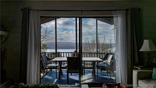 dining room with a water view, a wealth of natural light, and wood walls