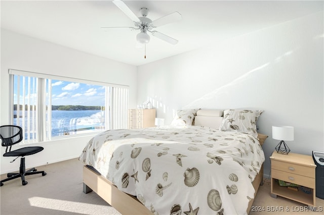 carpeted bedroom with a water view and ceiling fan