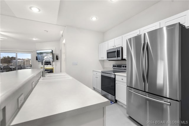 kitchen with stainless steel appliances, white cabinetry, and sink