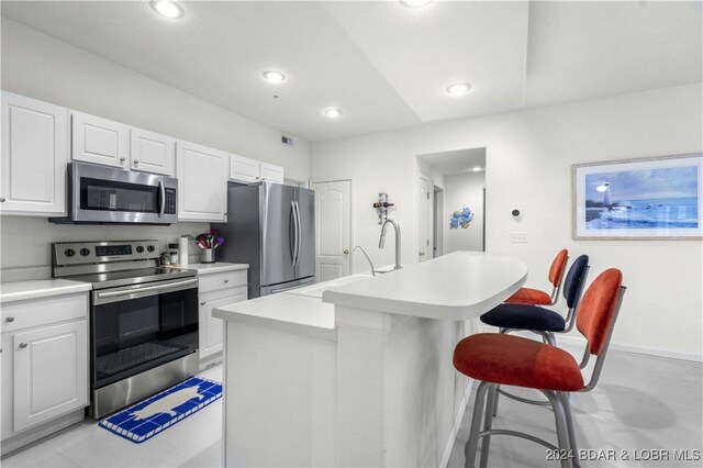 kitchen featuring stainless steel appliances, sink, white cabinets, a center island with sink, and a breakfast bar