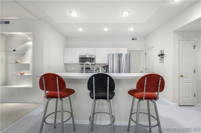 kitchen with stainless steel appliances, white cabinetry, and a breakfast bar