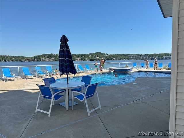 view of swimming pool featuring a patio and a water view