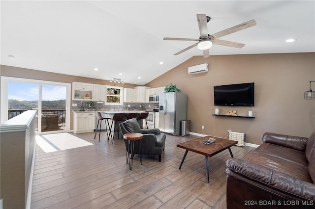 living room featuring ceiling fan, lofted ceiling, a wall mounted AC, and light hardwood / wood-style floors