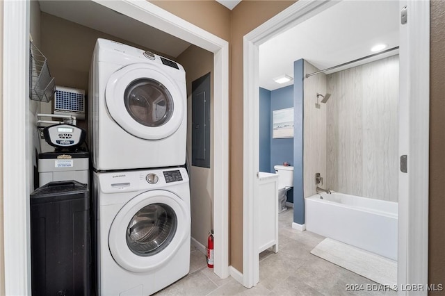 clothes washing area featuring stacked washer and dryer, light tile patterned floors, and electric panel