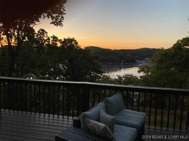 deck at dusk featuring a water view