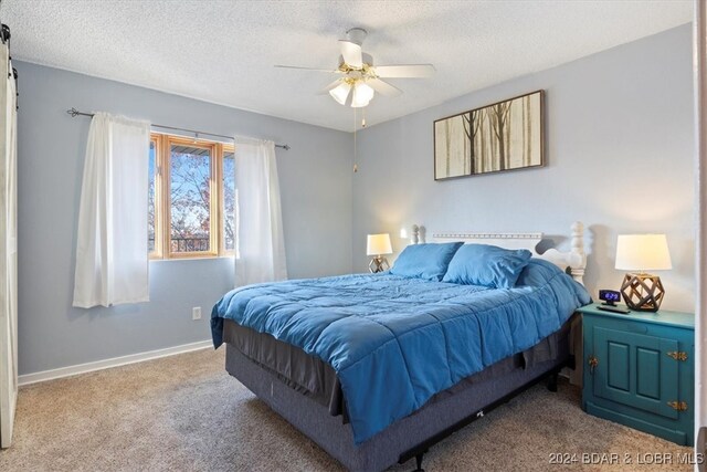 bedroom with ceiling fan, carpet floors, and a textured ceiling