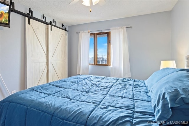 bedroom featuring a textured ceiling, a barn door, and ceiling fan