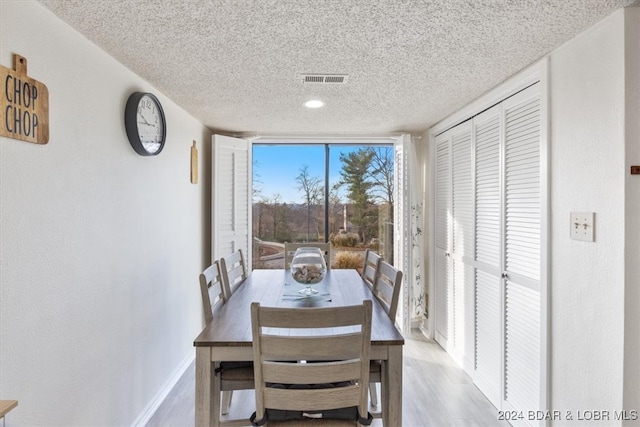 dining room featuring a textured ceiling and light hardwood / wood-style flooring