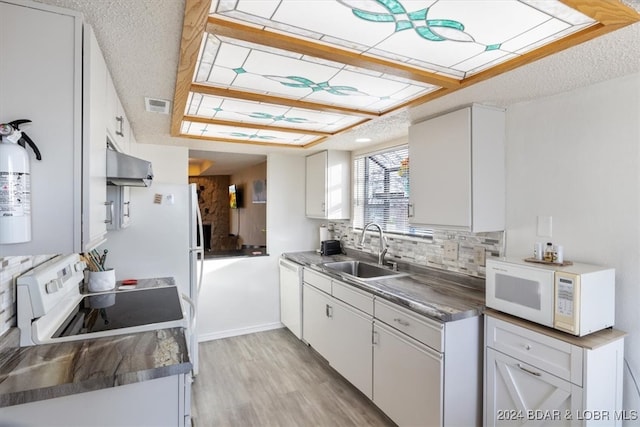 kitchen with backsplash, a textured ceiling, white appliances, sink, and white cabinetry