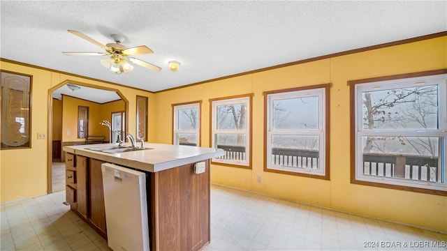 kitchen with a kitchen island with sink, dishwasher, a textured ceiling, and ornamental molding