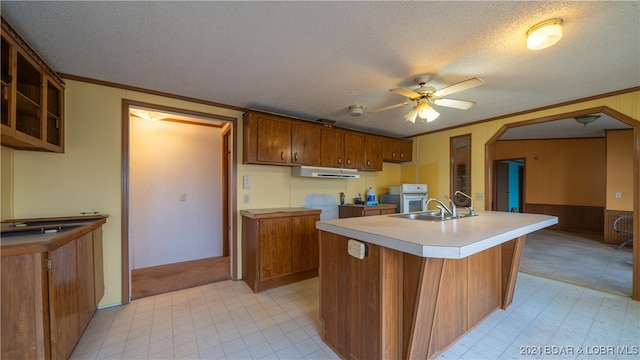 kitchen with ornamental molding, a textured ceiling, extractor fan, ceiling fan, and a center island with sink