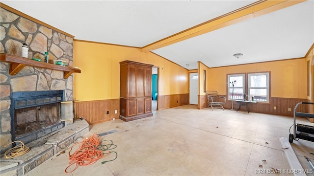 living room with crown molding, a fireplace, wooden walls, and vaulted ceiling