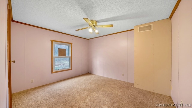 spare room with ceiling fan, crown molding, a textured ceiling, and light carpet