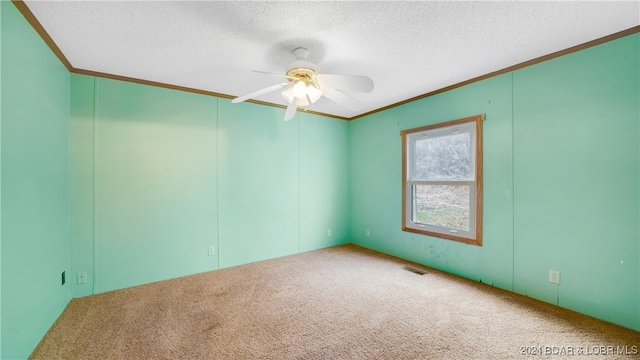 carpeted spare room with a textured ceiling, ceiling fan, and ornamental molding