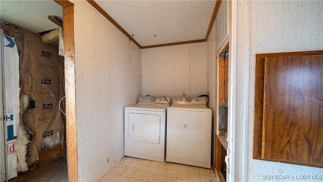 laundry room featuring washing machine and clothes dryer, a textured ceiling, and ornamental molding