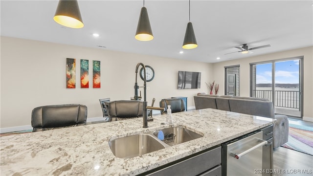 kitchen with light stone counters, dark hardwood / wood-style flooring, pendant lighting, and stainless steel dishwasher