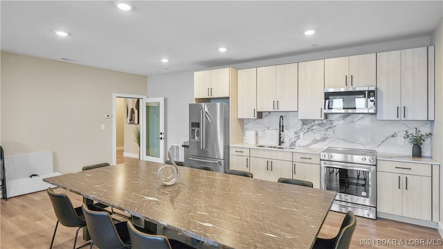 kitchen featuring hardwood / wood-style flooring, sink, a kitchen bar, and stainless steel appliances