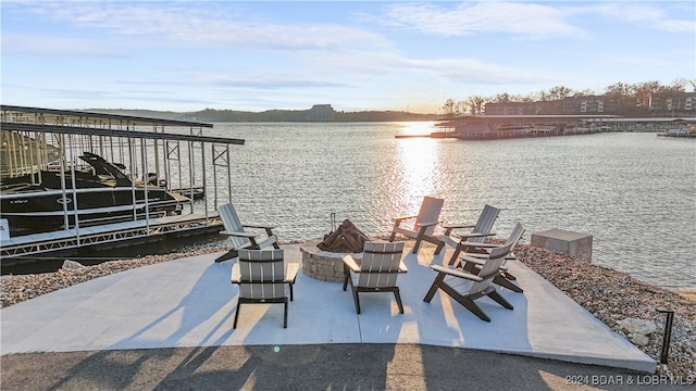 view of patio featuring a water view, a dock, and an outdoor fire pit