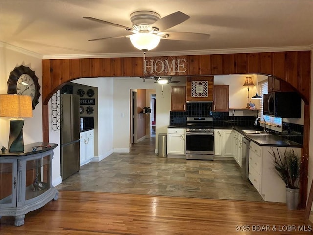 kitchen featuring sink, crown molding, tasteful backsplash, stainless steel appliances, and white cabinets