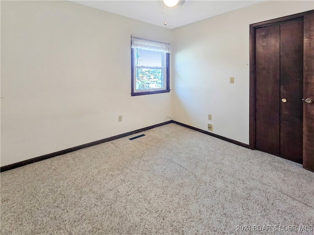 unfurnished bedroom featuring light carpet and a closet